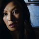 A woman stares straight ahead with wide eyes and a terrified look on her face.